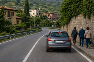 Automobile che rallenta prima di una curva con visibilità ridotta e presenza di pedoni vicino alla carreggiata